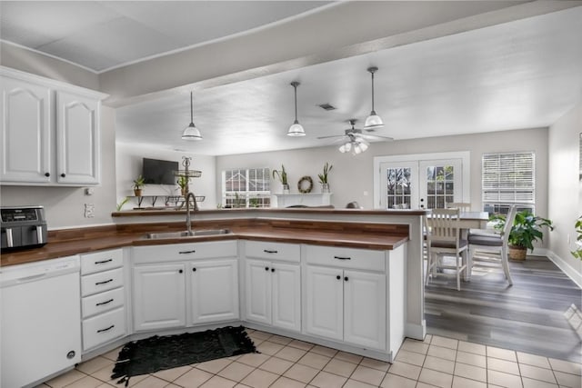 kitchen with hanging light fixtures, light wood-type flooring, sink, white dishwasher, and white cabinets