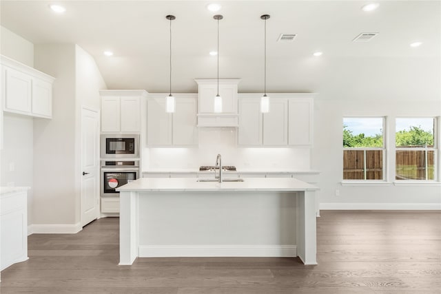 kitchen with a center island with sink, stainless steel oven, black microwave, and hanging light fixtures