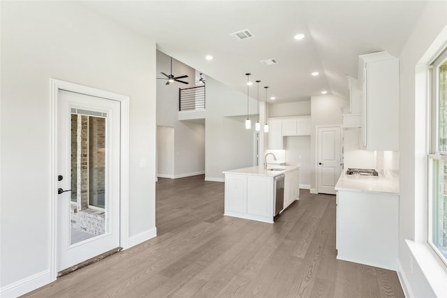 kitchen featuring appliances with stainless steel finishes, a kitchen island with sink, sink, white cabinetry, and hanging light fixtures