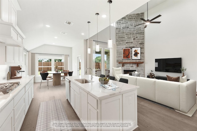 kitchen featuring white cabinets, sink, a kitchen island with sink, and vaulted ceiling