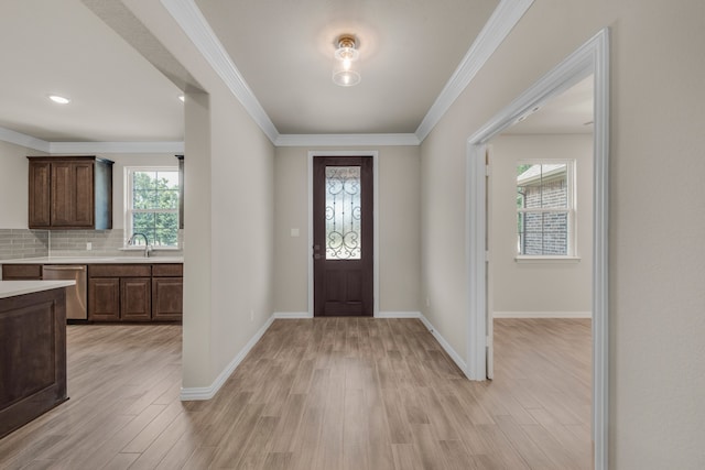 entrance foyer with sink, crown molding, and light hardwood / wood-style floors