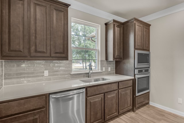 kitchen with light wood-type flooring, stainless steel appliances, decorative backsplash, dark brown cabinetry, and sink