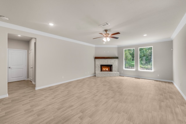 unfurnished living room with a stone fireplace, crown molding, light wood-type flooring, and ceiling fan