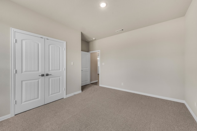 unfurnished bedroom with light carpet and a closet