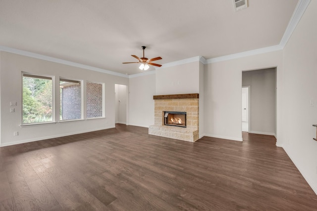 unfurnished living room with a stone fireplace, dark wood-type flooring, ornamental molding, and ceiling fan