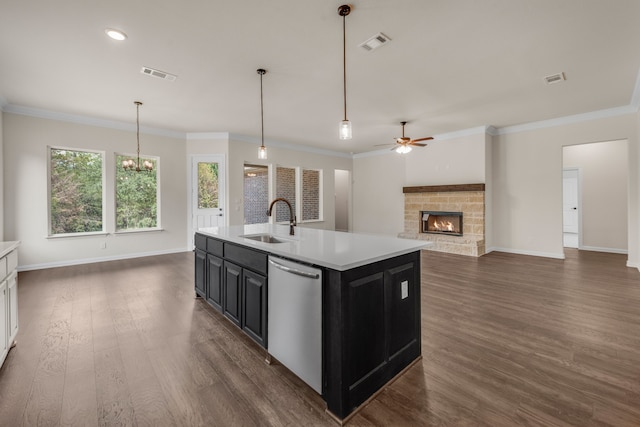 kitchen featuring stainless steel dishwasher, a kitchen island with sink, dark hardwood / wood-style floors, and a stone fireplace