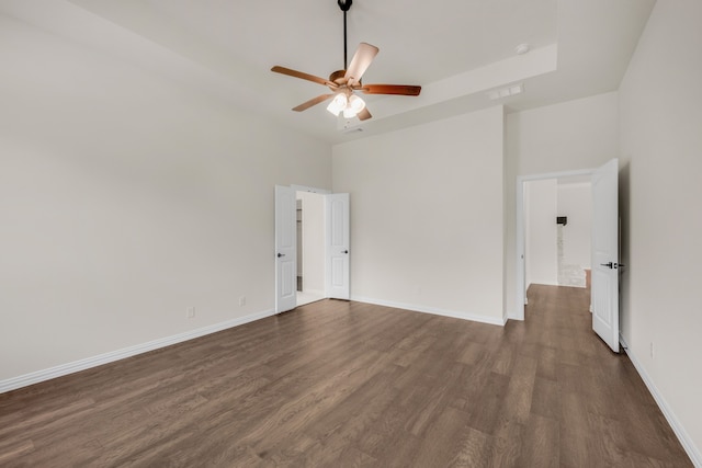 empty room featuring hardwood / wood-style flooring, a towering ceiling, and ceiling fan