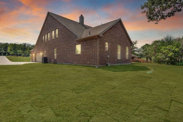 property exterior at dusk featuring a garage, central AC unit, and a lawn