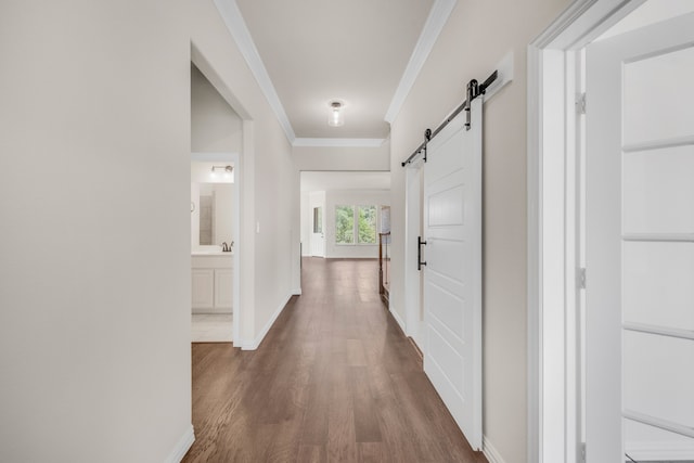 hall with ornamental molding, a barn door, and dark hardwood / wood-style floors