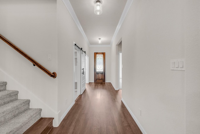 entryway featuring ornamental molding, a barn door, and dark hardwood / wood-style flooring