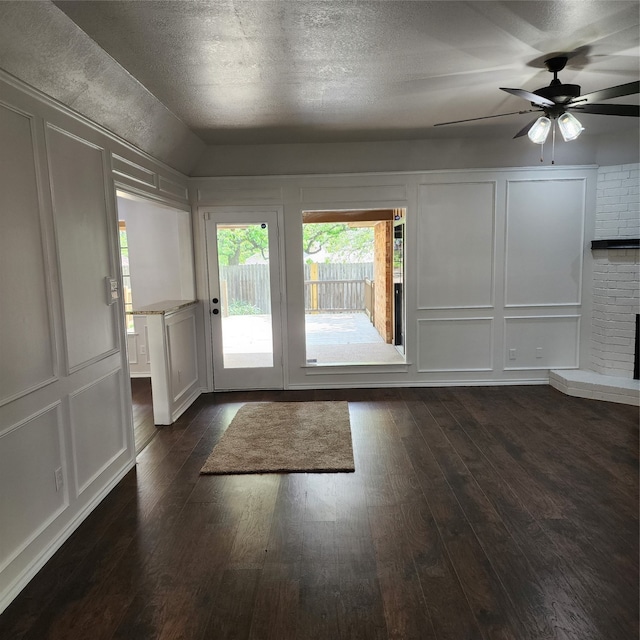 doorway featuring ceiling fan, a fireplace, a textured ceiling, and dark wood-type flooring