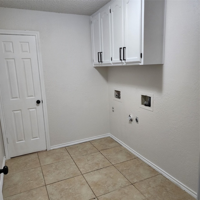 clothes washing area featuring a textured ceiling, cabinets, hookup for a washing machine, and light tile patterned floors