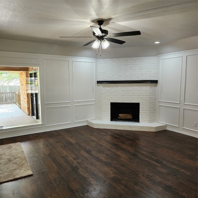 unfurnished living room with hardwood / wood-style floors, brick wall, a fireplace, a textured ceiling, and ceiling fan