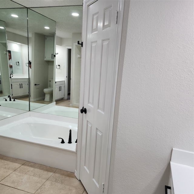 bathroom with tile patterned floors, a textured ceiling, vanity, and toilet