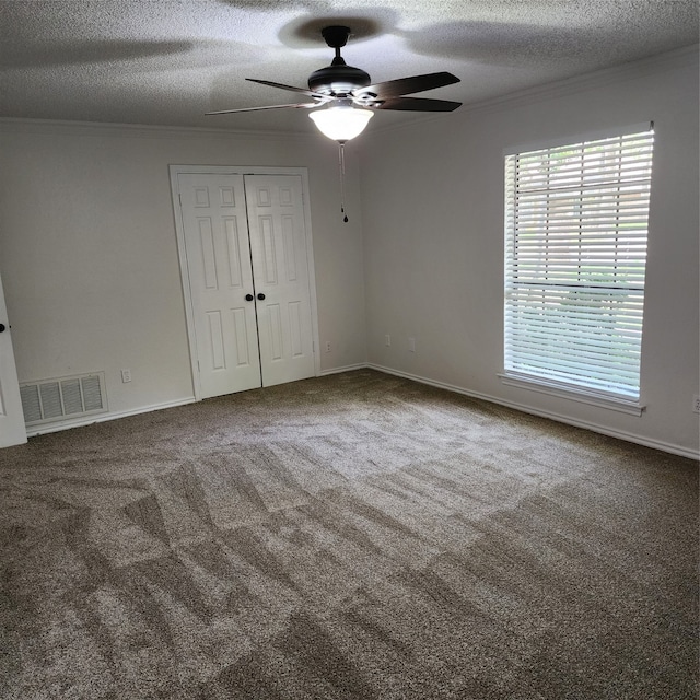 empty room with ceiling fan, plenty of natural light, a textured ceiling, and carpet flooring