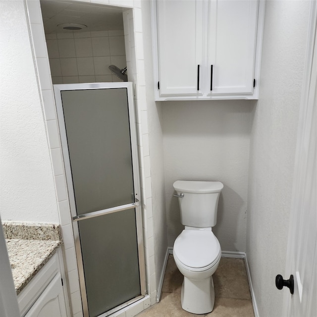 bathroom featuring tile patterned flooring, toilet, a shower with door, and vanity