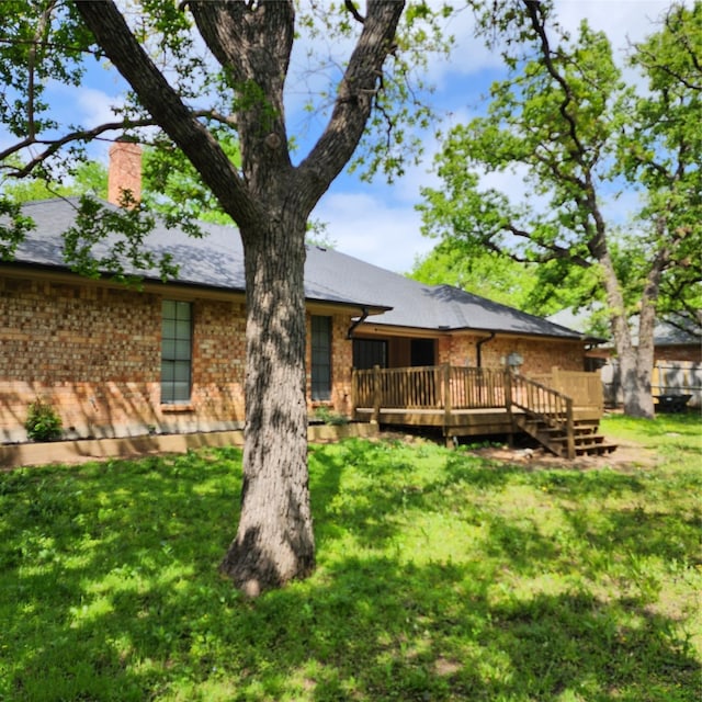 back of property with a wooden deck and a yard