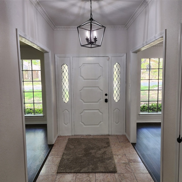 foyer entrance featuring light wood-type flooring, an inviting chandelier, and ornamental molding