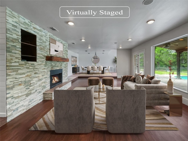 living room with dark hardwood / wood-style flooring and a stone fireplace