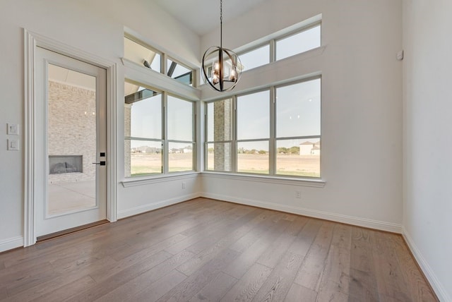 unfurnished dining area with plenty of natural light, a notable chandelier, and hardwood / wood-style flooring