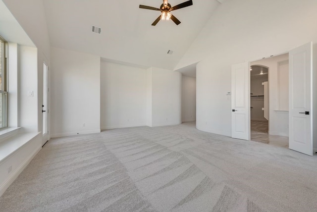 carpeted spare room with ceiling fan and high vaulted ceiling