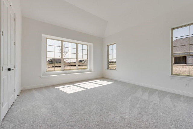 spare room with light carpet, a wealth of natural light, and vaulted ceiling