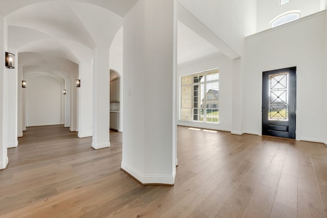 foyer entrance featuring light wood-type flooring, baseboards, and high vaulted ceiling