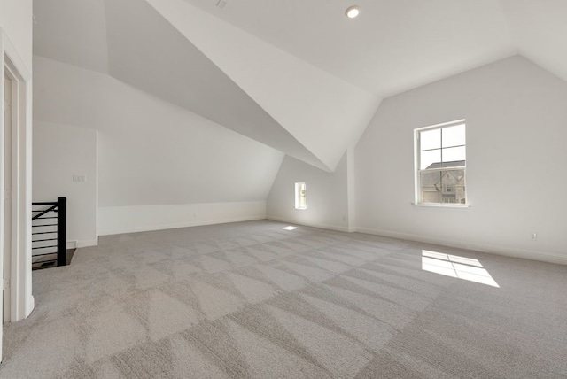 additional living space with light carpet and vaulted ceiling