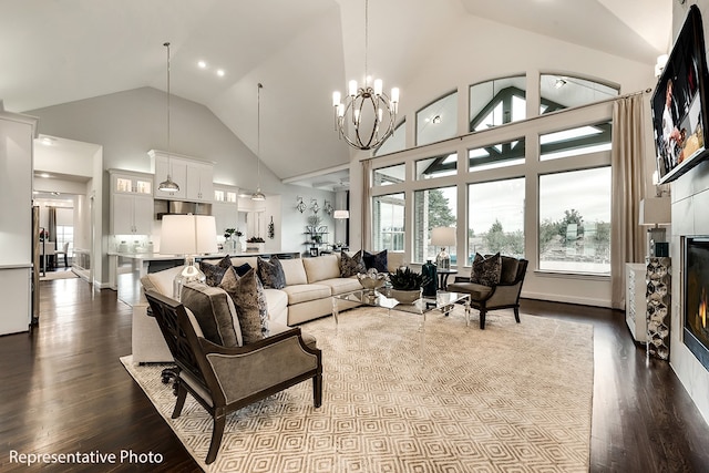 living room with a tile fireplace, hardwood / wood-style floors, high vaulted ceiling, and an inviting chandelier