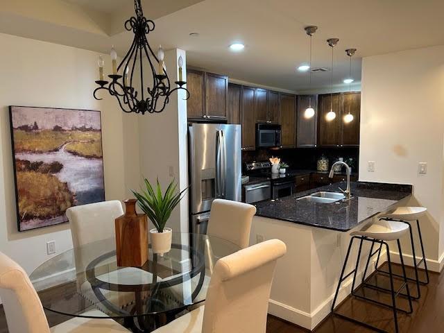 kitchen featuring a chandelier, a kitchen bar, stainless steel appliances, kitchen peninsula, and sink