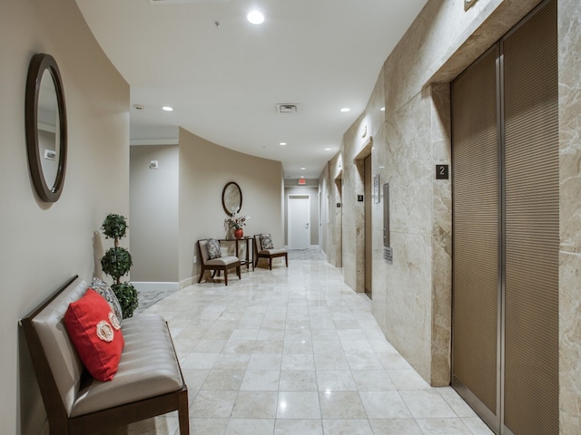 corridor featuring elevator and light tile patterned flooring