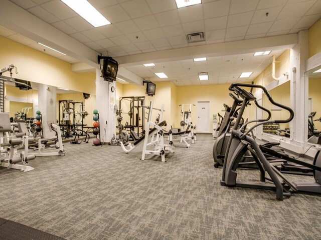 exercise room featuring a drop ceiling, visible vents, and carpet floors