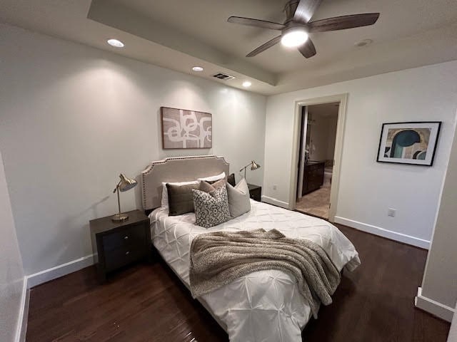 bedroom featuring a raised ceiling, ceiling fan, and dark hardwood / wood-style flooring