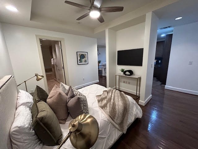 bedroom featuring dark hardwood / wood-style flooring, ensuite bathroom, and ceiling fan