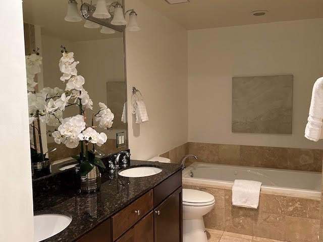 bathroom with vanity, toilet, tile patterned floors, and tiled bath