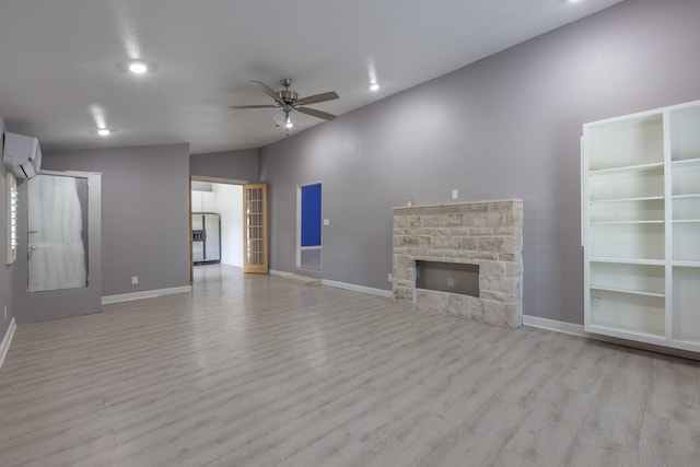 unfurnished living room featuring ceiling fan, wood finished floors, a wall mounted air conditioner, vaulted ceiling, and a fireplace