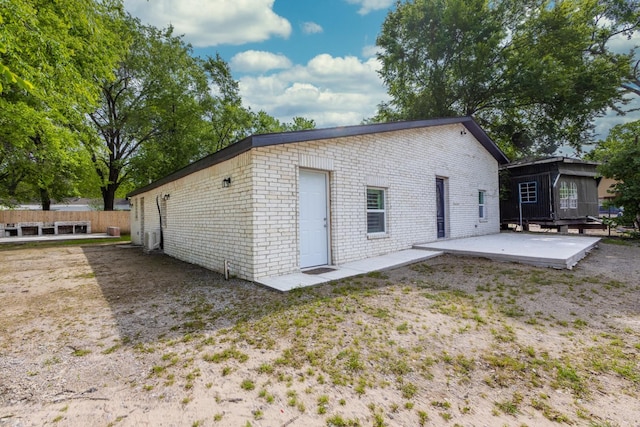 rear view of property with brick siding, a patio area, and fence