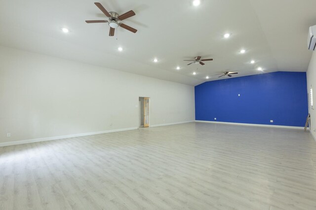 spare room with vaulted ceiling, light hardwood / wood-style floors, a wall unit AC, and ceiling fan