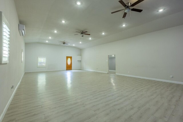 unfurnished living room featuring lofted ceiling, a stone fireplace, light hardwood / wood-style flooring, ceiling fan, and a wall unit AC