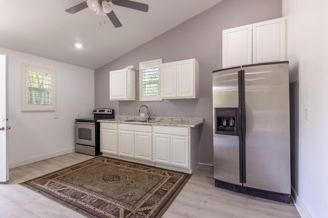 kitchen with white cabinets, appliances with stainless steel finishes, vaulted ceiling, light wood-type flooring, and a sink