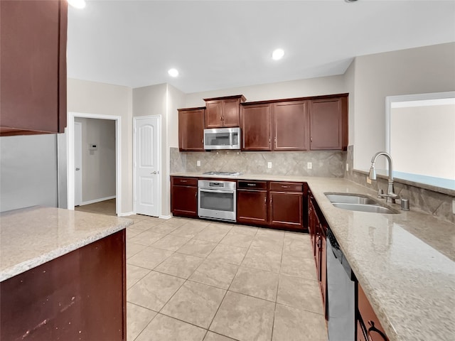 kitchen featuring tasteful backsplash, light stone counters, stainless steel appliances, light tile floors, and sink