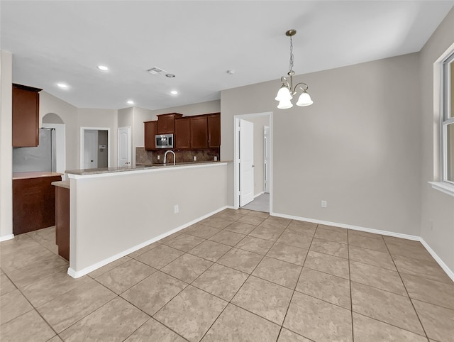 kitchen featuring stainless steel appliances, a notable chandelier, light tile flooring, tasteful backsplash, and hanging light fixtures