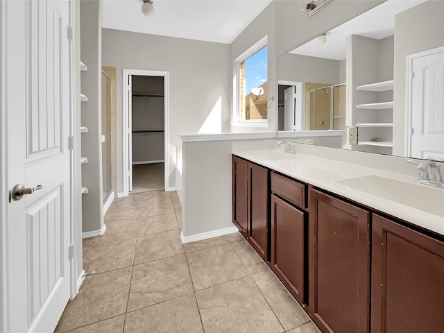 bathroom featuring a shower with shower door, dual bowl vanity, and tile floors