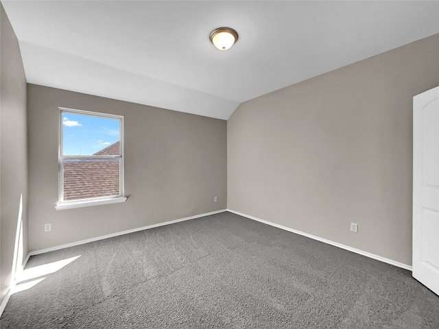 unfurnished room featuring lofted ceiling and dark carpet