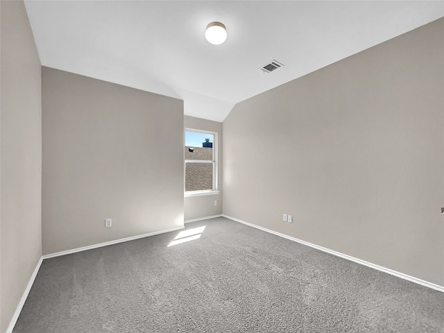 unfurnished room with dark carpet and lofted ceiling