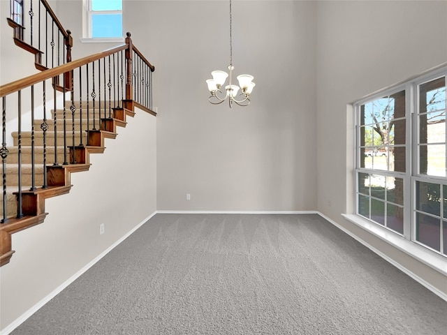 interior space with a high ceiling, a notable chandelier, and carpet