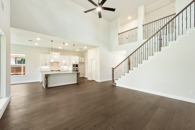 unfurnished living room with stairs, dark wood-style flooring, baseboards, and recessed lighting