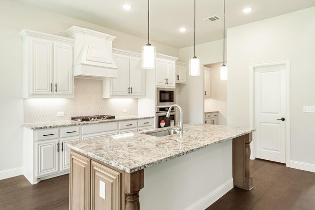 kitchen with visible vents, dark wood-style floors, appliances with stainless steel finishes, premium range hood, and a sink