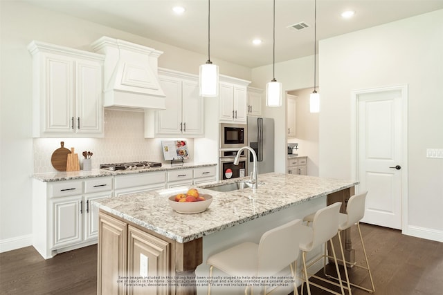 kitchen with stainless steel appliances, a sink, visible vents, dark wood finished floors, and custom range hood