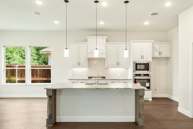 kitchen with appliances with stainless steel finishes, an island with sink, visible vents, and decorative backsplash